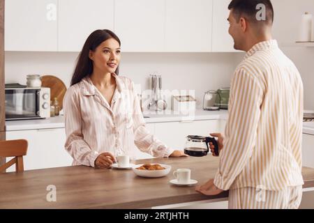 Happy young couple having breakfast in kitchen Stock Photo