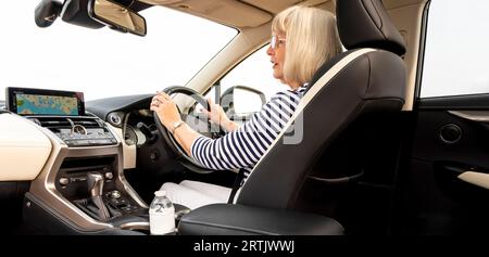 Portsmouth, England, UK. 29 August 2023.  Woman motorist holding steering in a luxury car, checking the rear view mirror. Stock Photo