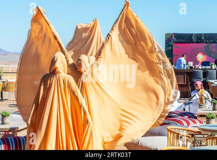 Saudi Arabian women in traditional fully covered golden clothes are dancing on the camel cup race performance, Al Ula, Saudi Arabia Stock Photo