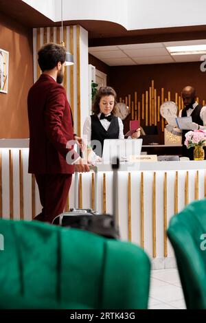 Hotel concierge reviewing id documents to assist businessman with check in process, work trip. Receptionist greeting guest and looking at his passport, online room reservation. Stock Photo