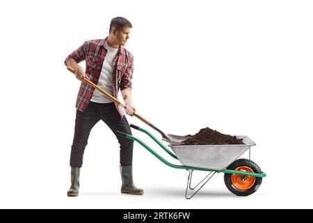 Farmer putting earth in a wheelbarrow with a shovel isolated on white background Stock Photo