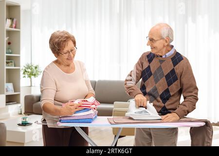 Senior couple ironing together at home in a living room Stock Photo