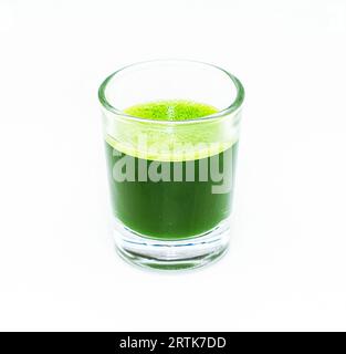 Healthy green wheat grass shot in small glass isolated on white Stock Photo