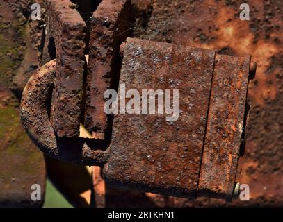 Rusted padlock on a rusty metal post. Isolated closeup corroded padlock, iron oxide corrosion process detailed image. Stock Photo