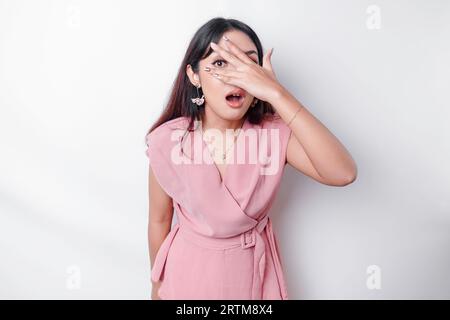 Funny obvious peeking Asian woman in pink blouse isolated on white background. Stock Photo
