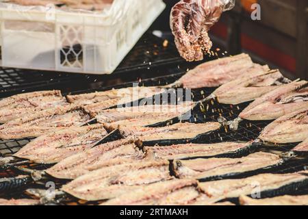 Flavouring fresh mackerel fish in a mobile smokehouse in a farmer's street market in Vilnius, Lithuania Stock Photo