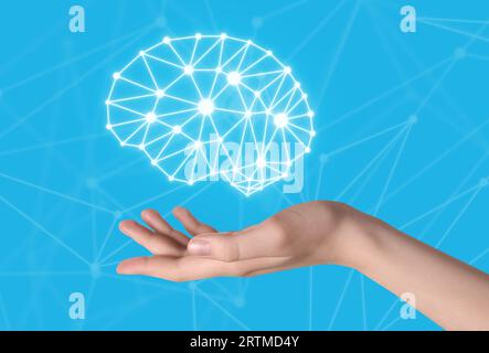 Memory. Woman holding illustration of brain against light blue background with scheme, closeup Stock Photo