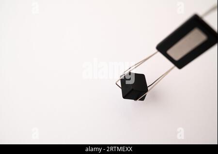 A close-up of a mechanical keyboard keycap placed inside a keycap and switch puller tool on a white background. Copy space. Stock Photo