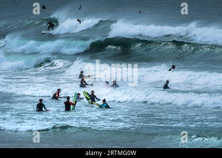 Surfers and boogie boarders in the waves, Hayle Bay, Polzeath, Cornwall ...