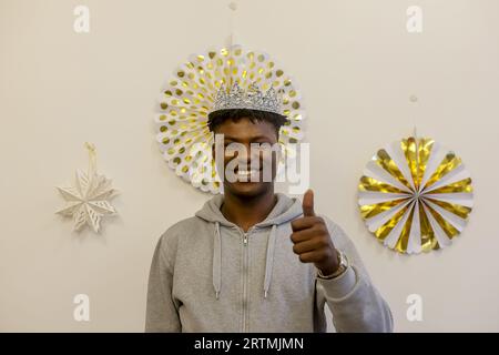Traditional Epiphany celebration at La Maison Bakhita, Paris, France. Migrant wearing a cardboard crown Stock Photo