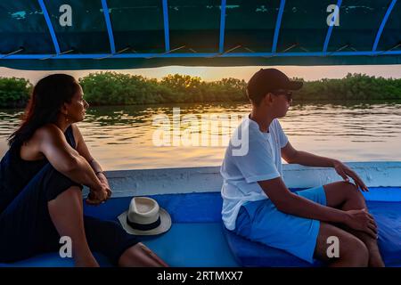 Mother and son on a boat cruising in the Saloum river delta at dusk, Senegal Stock Photo