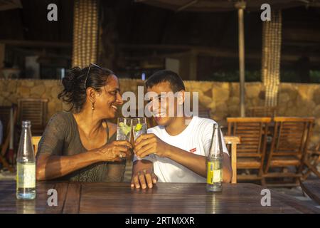 Mother and son clinking glasses in a bar in Ndayane, Senegal Stock Photo