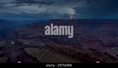 Distant and dreamy lightning strikes beyond the north rim seen from the Grand Canyon during twilight’s blue hour. Stock Photo