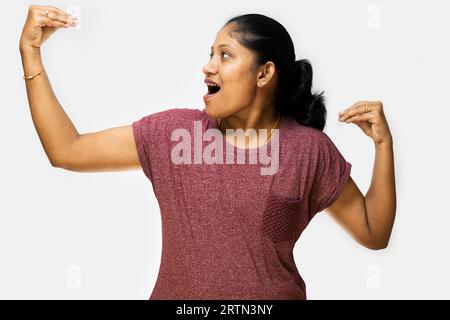 A young woman with long brown hair and brown eyes looks up in surprise, her hands open wide. She is wearing a red t-shirt and jeans. Stock Photo