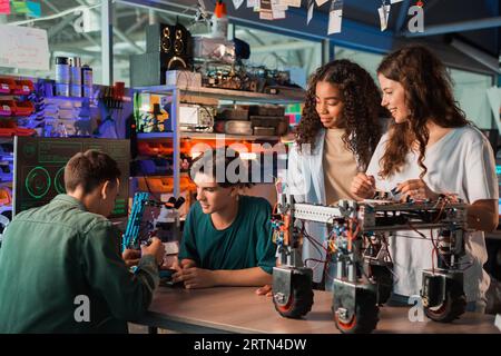 Group of young people doing experiments in robotics in a laboratory. Robot and tools on the table Stock Photo