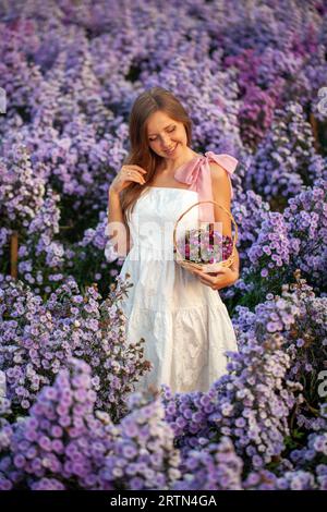 Woman in a summer dress, surrounded by wildflowers at sunset Stock Photo