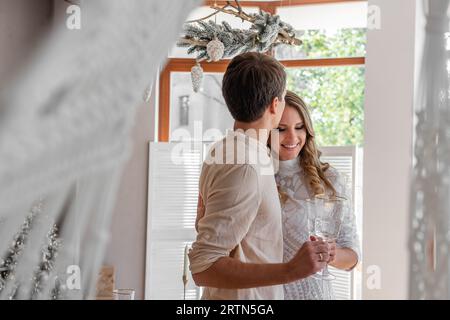 Close-up portrait of loving, young fashion couple with glasses of champagne in Christmas. Trendy interior in Scandinavian style with panoramic window Stock Photo