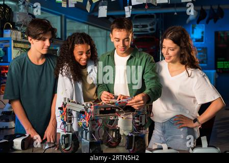 Group of young people doing experiments in robotics in a laboratory. Robot and tools on the table Stock Photo