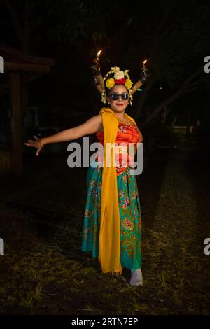 a traditional Javanese dancer stands and dances with a flexible body while wearing sunglasses at night Stock Photo