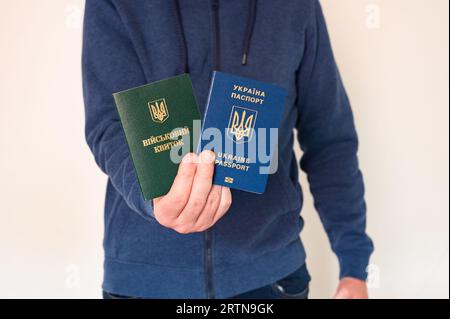 Translation: 'military id'. Civil man in blue sweatshirt with ukrainian foreign passport and army document for soldiers, rookies and civils in hand Stock Photo