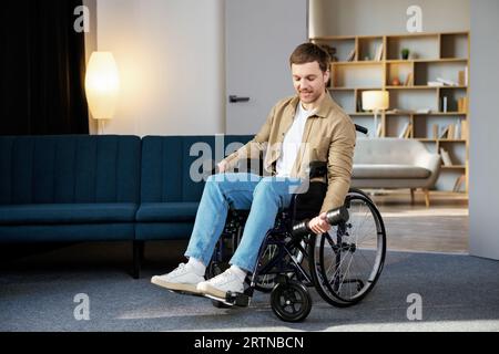 Physical rehabilitation for disabled people. Happy guy in wheelchair making exercises with dumbbell at home. Cheerful impaired young man working out w Stock Photo