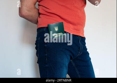 Translation: 'military id'. Civil man in red t-shirt with ukrainian military id in jeans pocket. Soldier, mobilization, veteran, rookie, document, bor Stock Photo