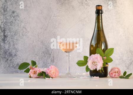 Glass of pink champagne with rose flowers on the light grey background Stock Photo