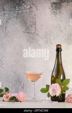 Glass of pink champagne with rose flowers on the light grey background Stock Photo