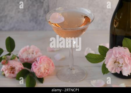 Glass of pink champagne with rose flowers on the light grey background Stock Photo