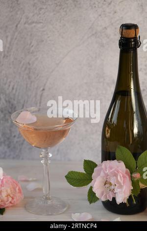 Glass of pink champagne with rose flowers on the light grey background Stock Photo