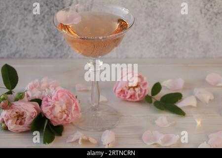 Glass of pink champagne with rose flowers on the light grey background Stock Photo