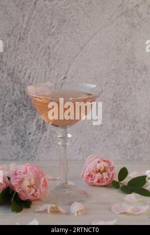 Glass of pink champagne with rose flowers on the light grey background Stock Photo