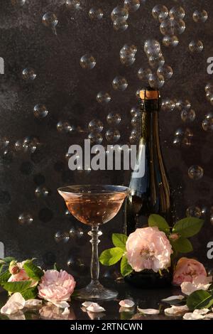 Glass of pink champagne with rose flowers on the black background with bubbles Stock Photo