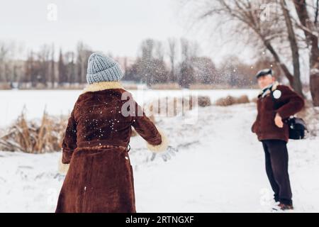 Senior family couple playing snowballs outdoors during snowy winter weather. Elderly people having fun walking. Valentine's day Stock Photo