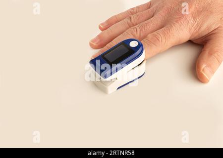 Man using a portable finger heart pulse meter on a white background with copy space Stock Photo