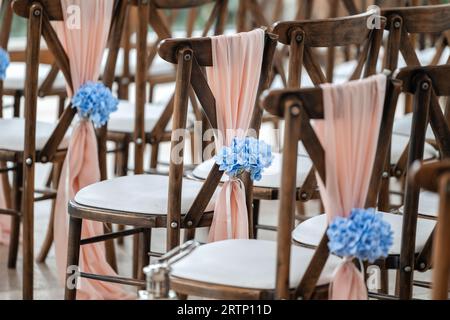 Beautiful wedding venue seats with blue flowers and sashes for ceremony Stock Photo