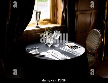 Romantic table for two in restaurant for valentines day. Wineglasses summer sunshine and flowers on the table Stock Photo