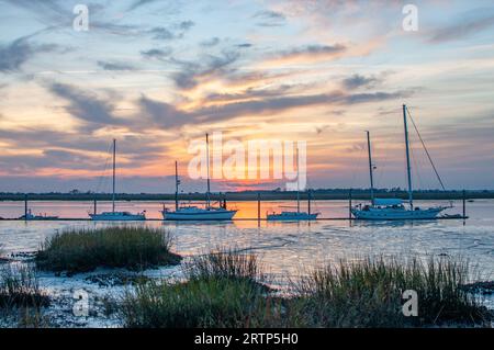 Boats on the river marsh at dusk with a colorful sunset in Jekyll Island, Georgia Stock Photo