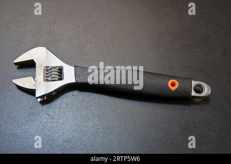 Adjustable wrench with measuring tool on black wooden table Stock Photo
