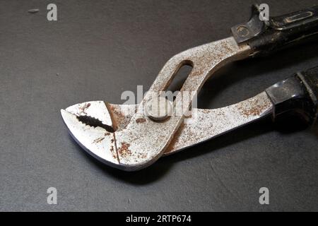 Locking plier head on black wooden table in close up Stock Photo