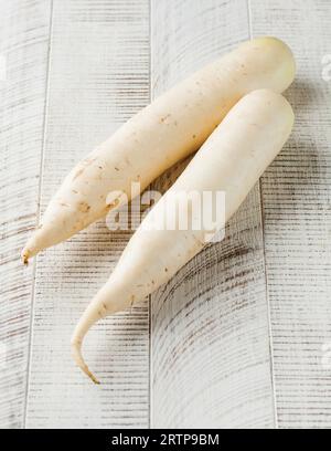 Daikon on a white wooden background. Healthy food, vegetables. Stock Photo