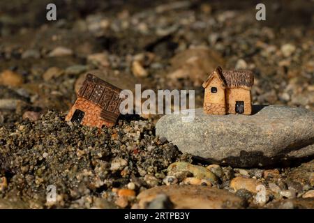 Two miniature houses in sand and on rock (stone). Close-up. Wise and solid foundation gospel parable of Jesus Christ, obedience, and faith in God. Stock Photo