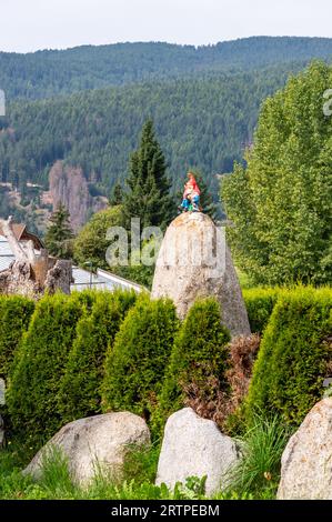 garden gnomes on top of a rock with mountains in the background Stock Photo