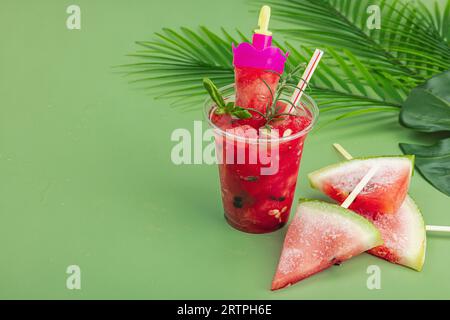 Refreshing watermelon cocktail. Traditional summer drink. Trendy Savannah green background, palm leaves, copy space Stock Photo
