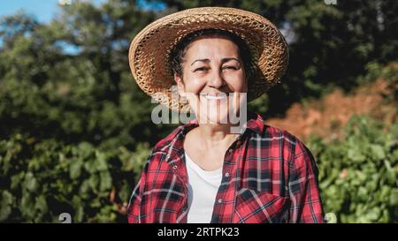 Happy Latin senior farmer woman work at rural farm smiling at camera - Small business agriculture and harvest concept Stock Photo