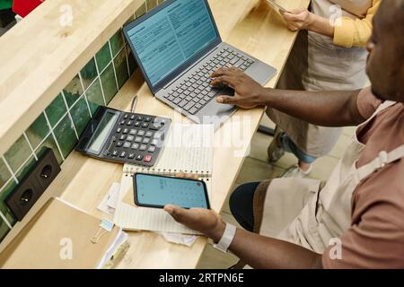 High angle view of colleagues working with finance in team using laptop at table in supermarket Stock Photo