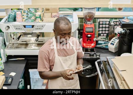 African American barman working online on digital tablet Stock Photo