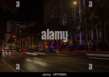 Night view of Miami Beach cityscape with police cars and defocused light tracers of cars on Collins Avenue. Miami Beach. USA. Stock Photo