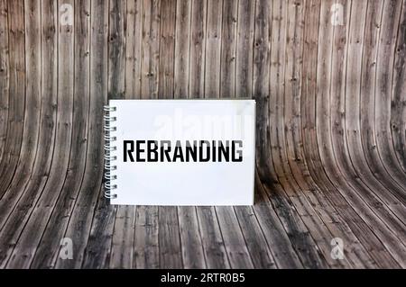 The word REBRANDING on a notepad and wooden background. Stock Photo
