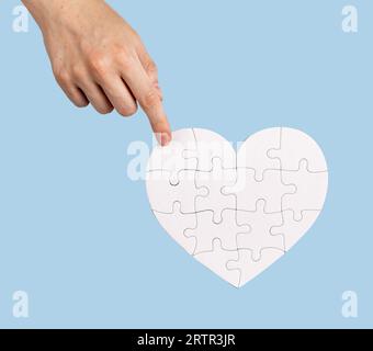 The final touch. Placing the missing puzzle piece to heart-shaped jigsaw Stock Photo